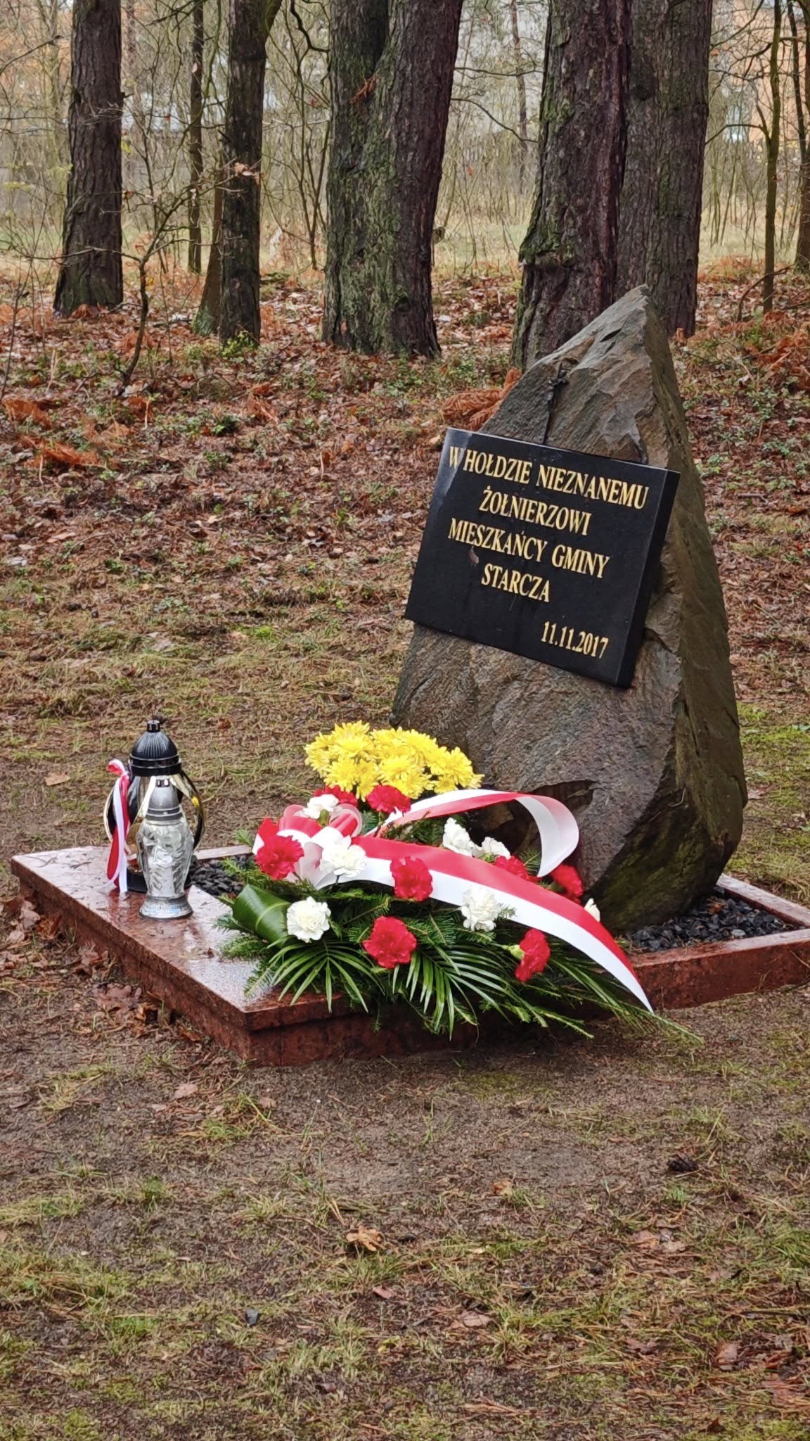 Na zdjęciu znajduje się pomnik Grobu Nieznanego Żołnierza z zapalonym zniczem i wiązanką kwiatów