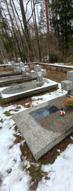 Widoczny jest nagrobek oraz tablica z inskrypcją, gdzie został zapalony i złożony znicz.