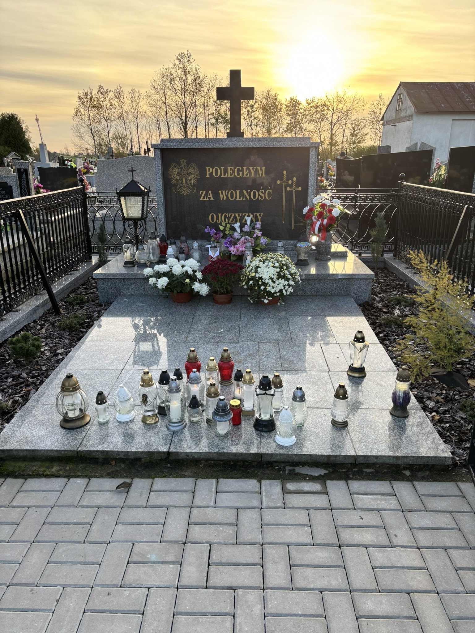 Na obrazku znajduje się grób zbiorowy poległych za Ojczyznę, z kamiennym pomnikiem i krzyżem.