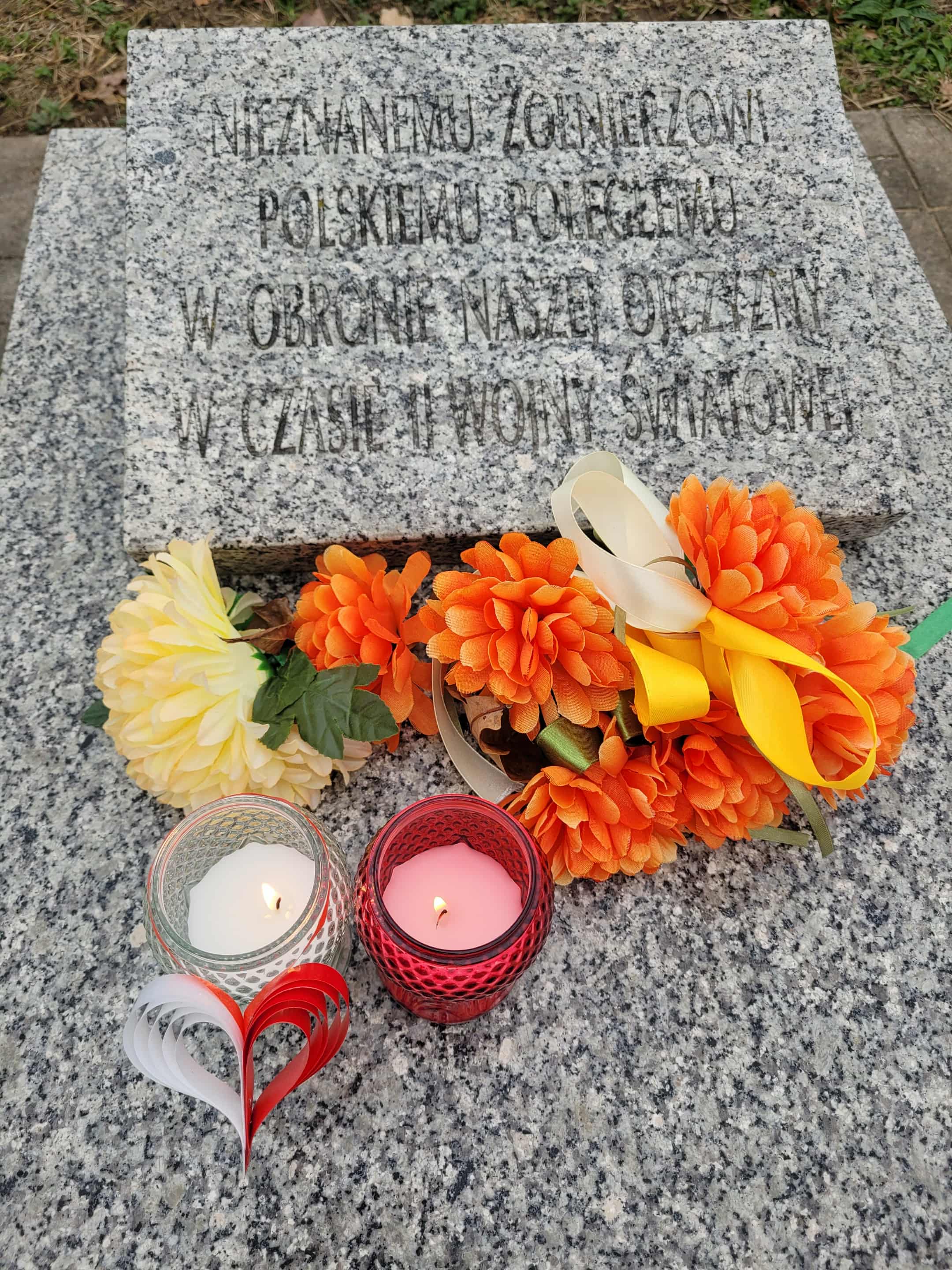Zdjęcie przedstawia niewielki grób wykonany z jasnoszarego granitu.