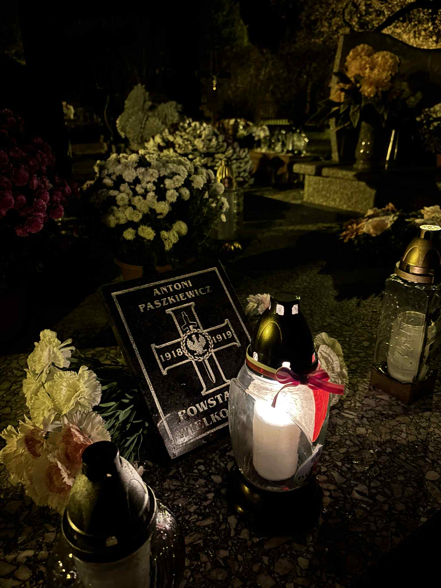 Tablica "Antoni Paszkiewicz, Powstaniec Wielkopolski" a obok niej znicz