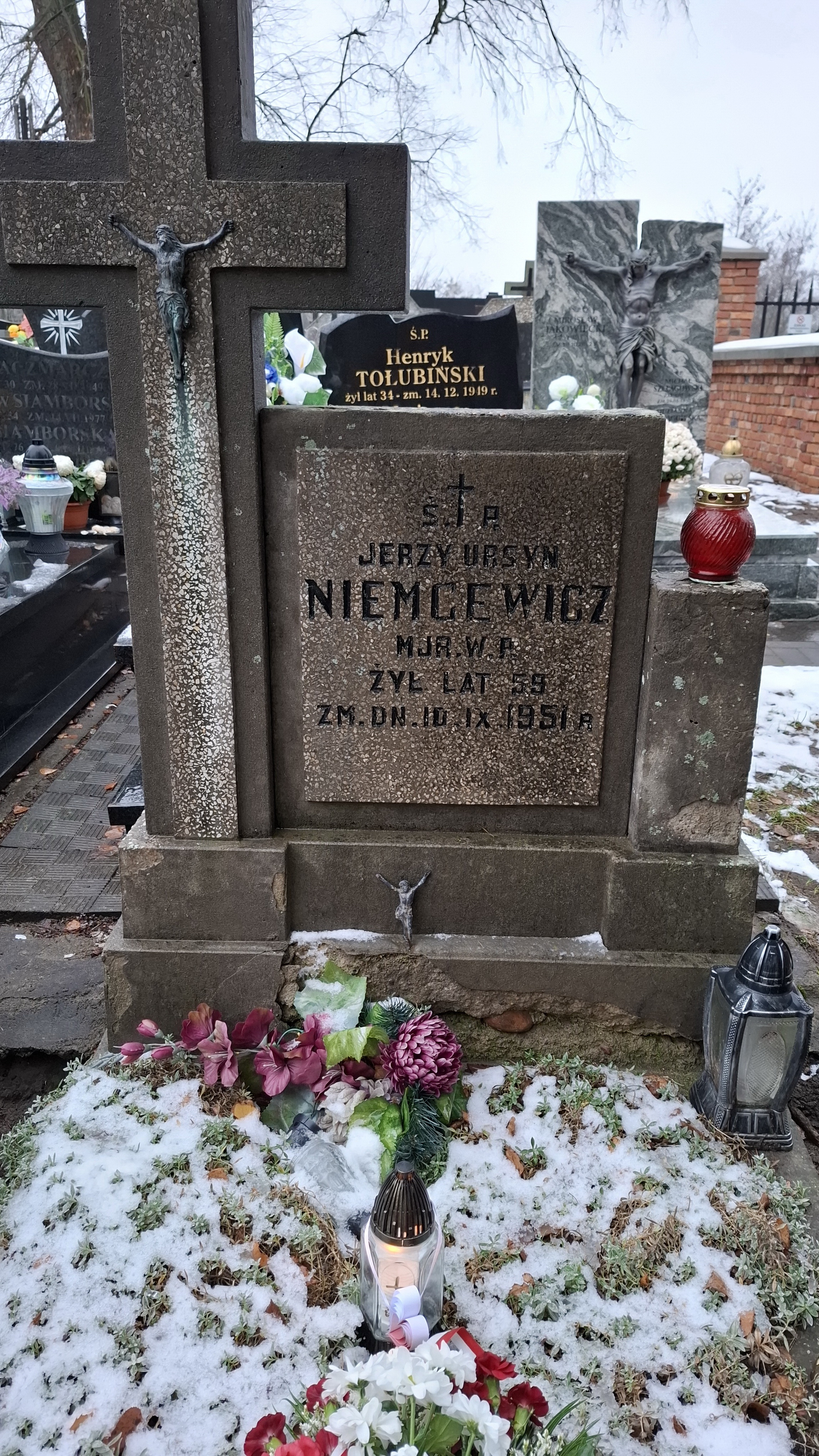 Znicz z zawieszonym papierowym biało-czerwonym sercem oraz bukiet kwiatów z biało-czerwoną wstążką