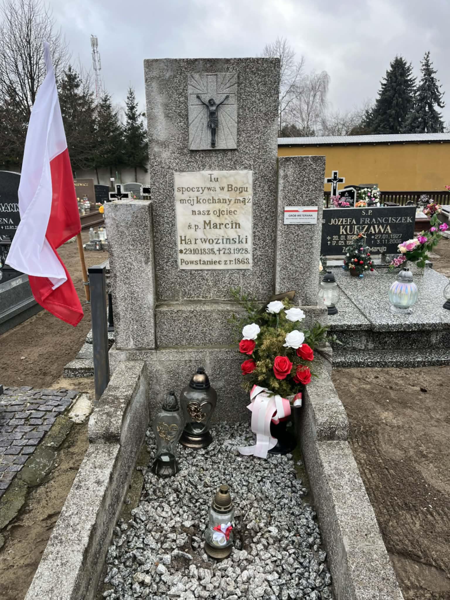 Nagrobek grafitowy z umieszonym krzyżem powstańczym oraz tabliczką weterana wojennego.