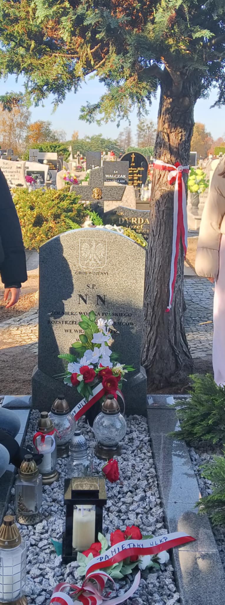 Na zdjęciu znajduje się fragmentu groby wraz z zapalonym zniczem.