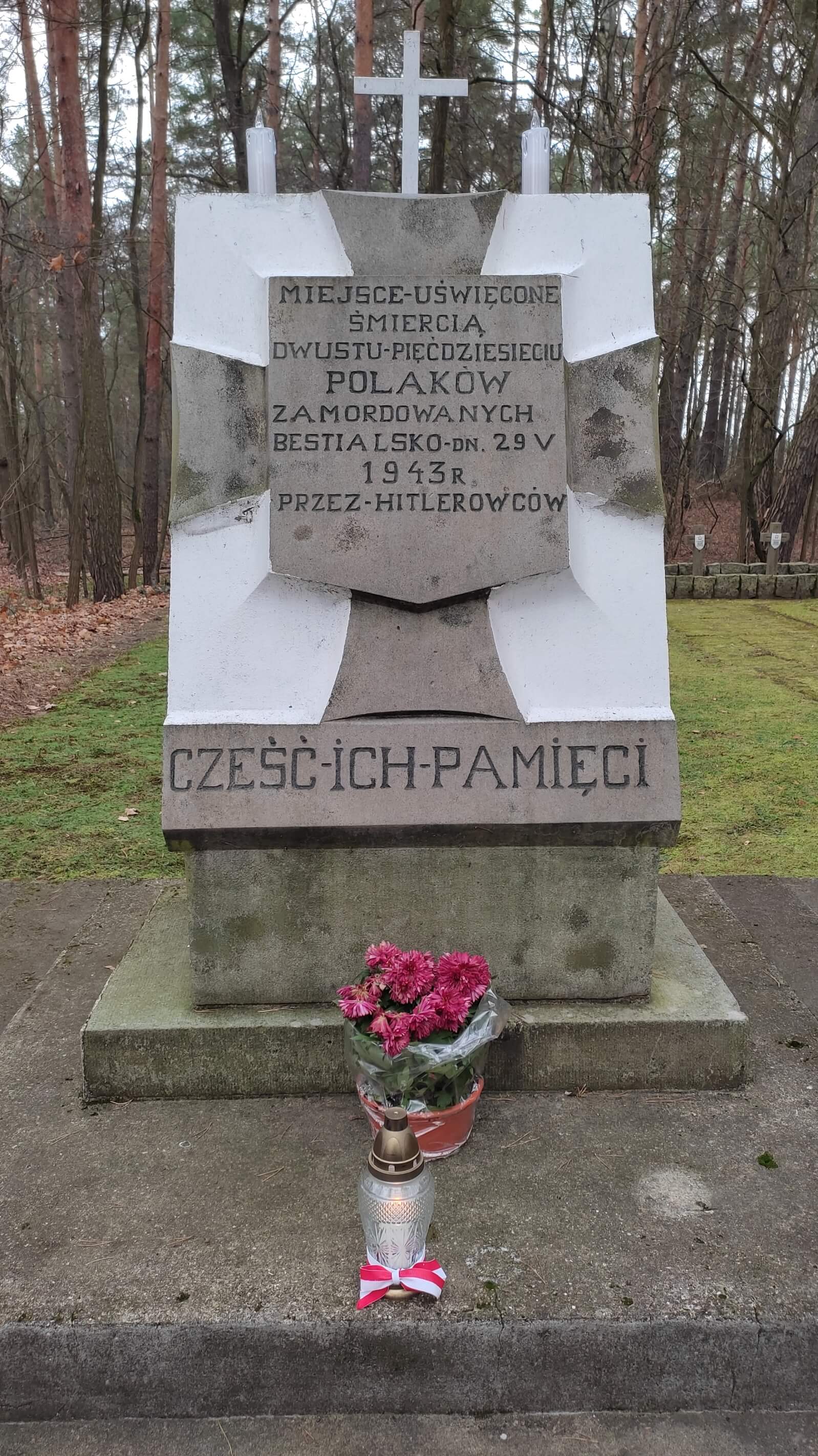 Miejsce rozstrzelania cywilnej ludności, pamiątkowy obelisk oraz zapalony "ZNICZ PAMIĘCI" z szarfą