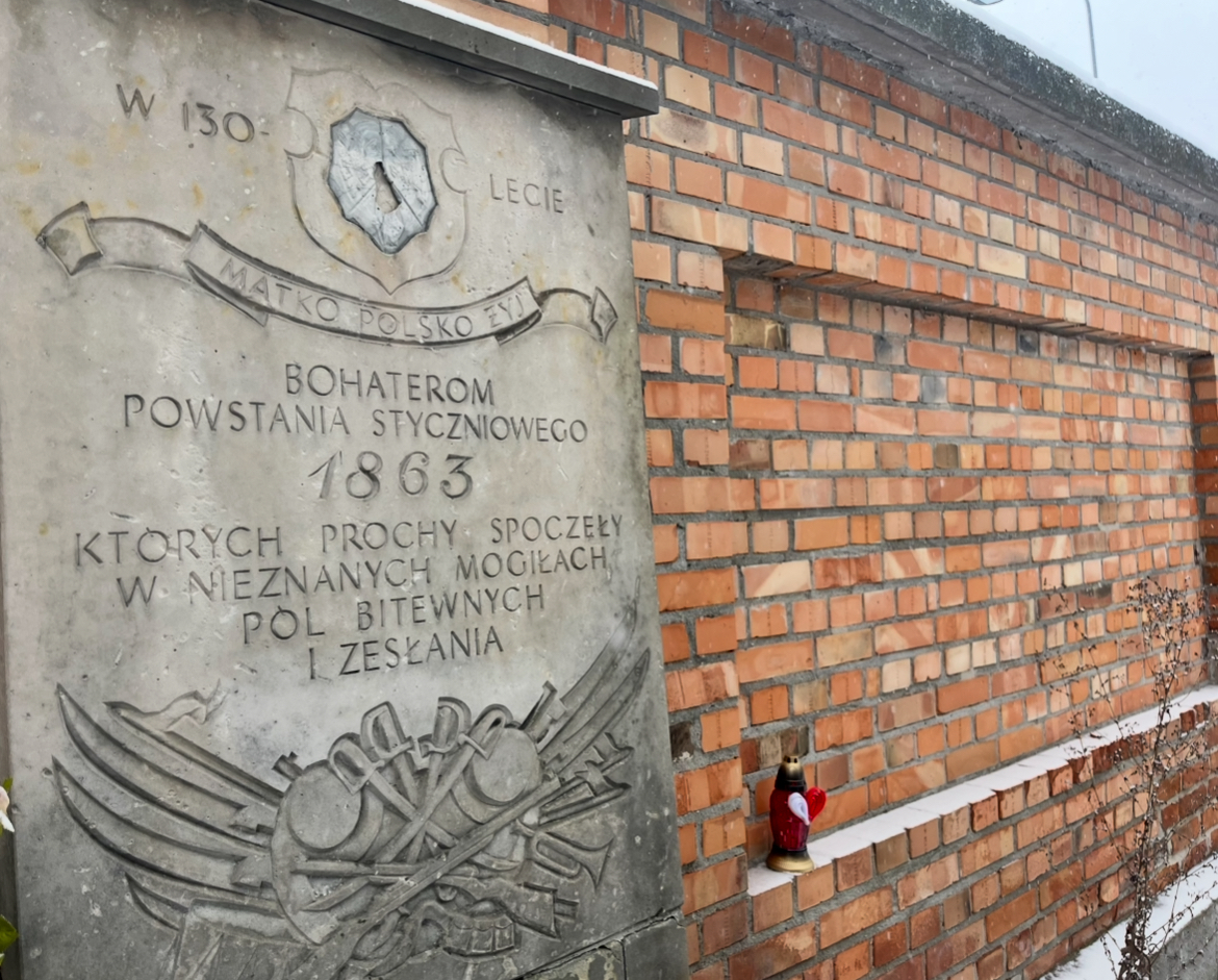 Zdjęcie przedstawia kamienną tablicę pamiątkową wmurowaną w ceglany mur.